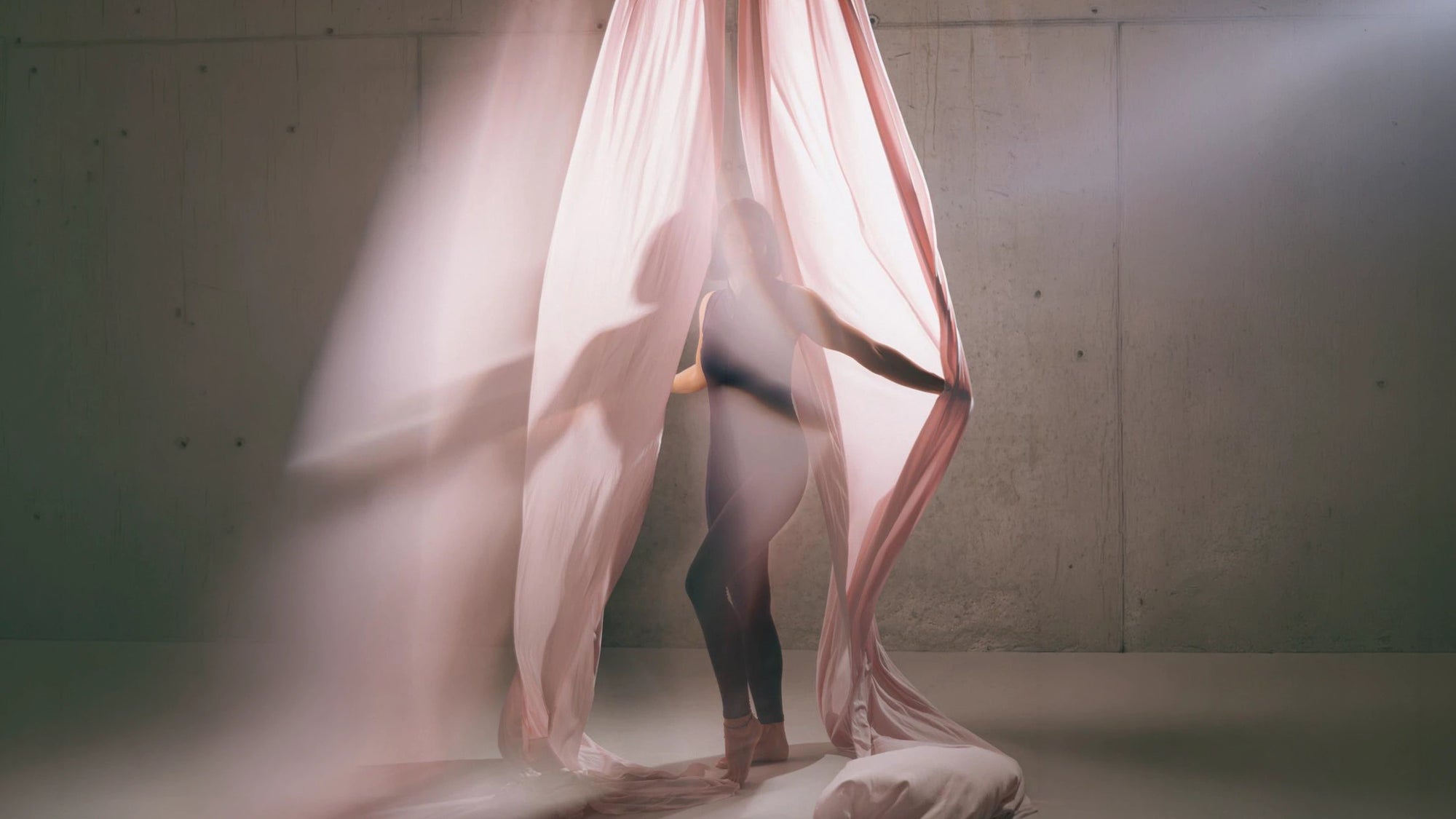 Aerial Artist in einem rosafarbenen luftseide Tuch im lichtdurchfluteten Studio
